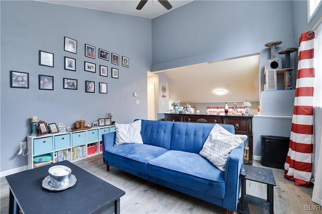living area with high vaulted ceiling, baseboards, a ceiling fan, and wood finished floors