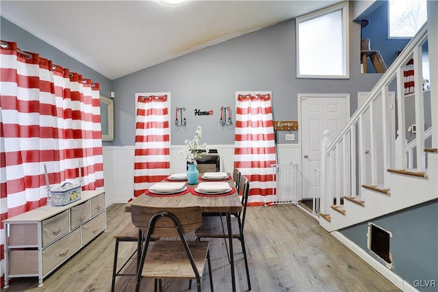 unfurnished dining area with wood finished floors, vaulted ceiling, and stairs