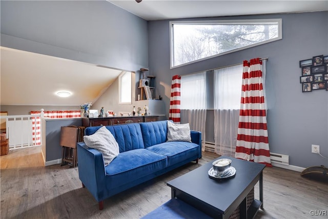 living area with a baseboard heating unit, plenty of natural light, and wood finished floors