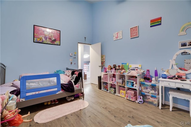 recreation room featuring a high ceiling and wood finished floors