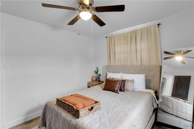 bedroom with a ceiling fan, baseboards, and wood finished floors