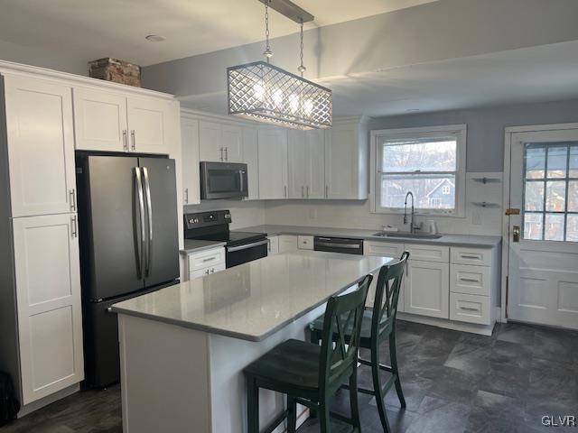 kitchen with a kitchen bar, white cabinetry, a sink, and black appliances