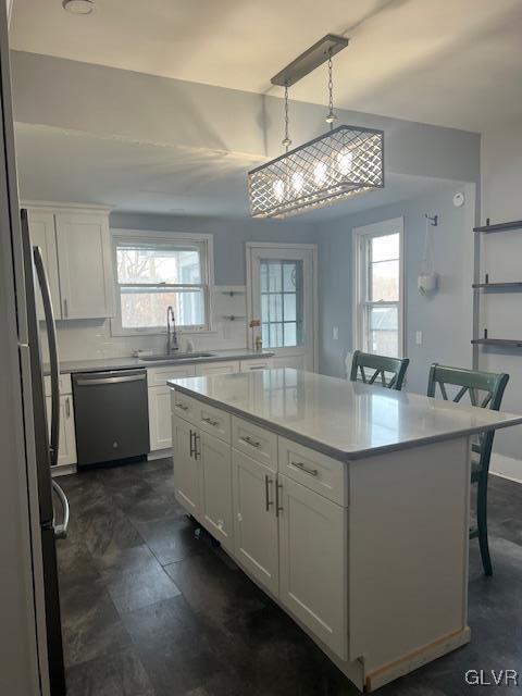 kitchen with light countertops, white cabinets, a sink, and stainless steel dishwasher