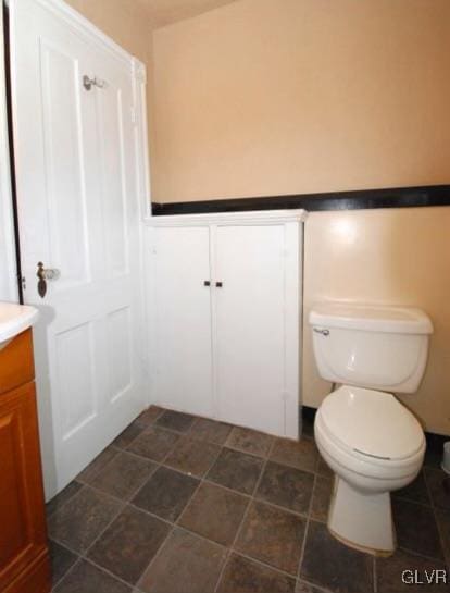 bathroom with wainscoting, vanity, and toilet