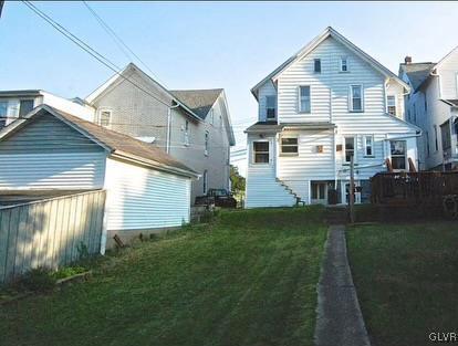 rear view of house with fence and a lawn