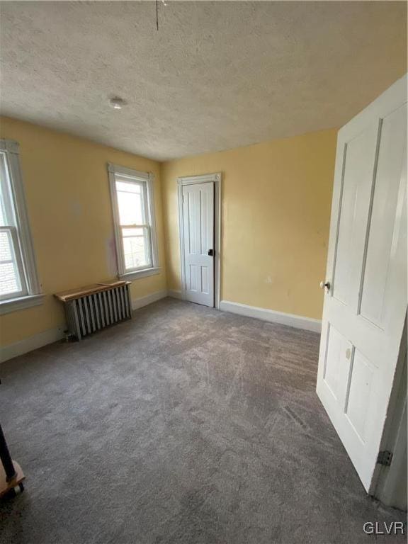 interior space featuring a textured ceiling, radiator heating unit, and baseboards