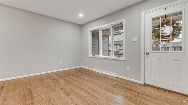 spare room featuring a baseboard radiator, baseboards, and wood finished floors