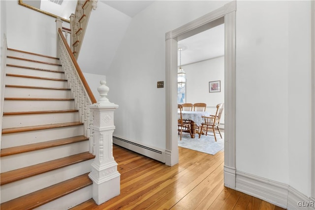 stairs with a baseboard radiator, visible vents, and hardwood / wood-style floors