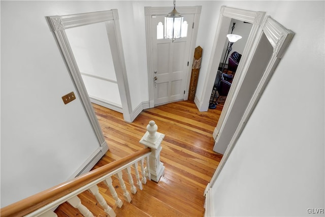 entrance foyer with baseboards, stairway, an inviting chandelier, and light wood-style floors