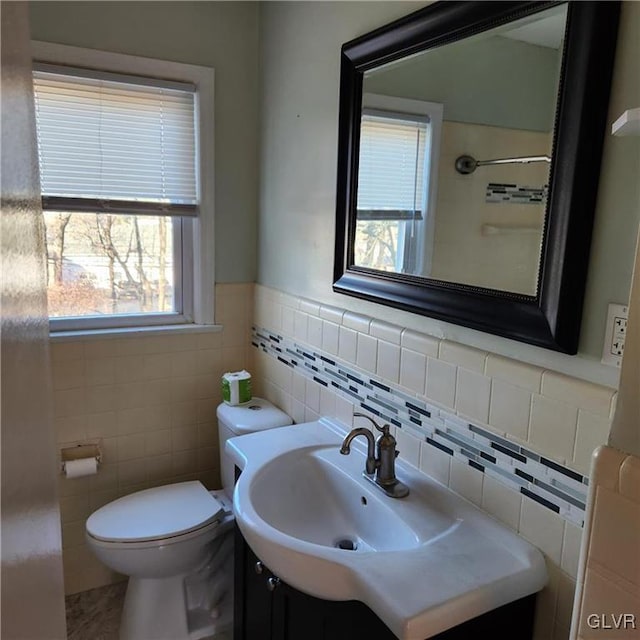 bathroom featuring wainscoting, vanity, toilet, and tile walls