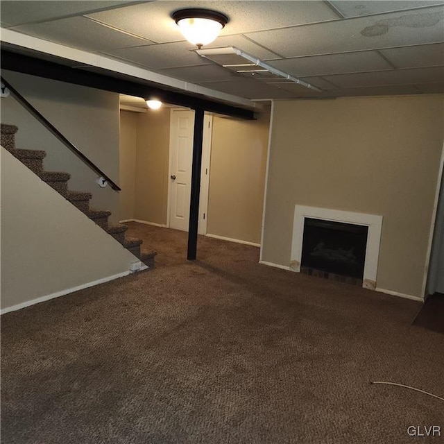 finished below grade area featuring baseboards, stairs, carpet flooring, a paneled ceiling, and a fireplace