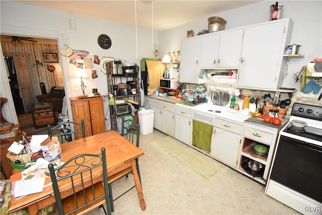 kitchen with white microwave, range with electric cooktop, white cabinetry, light countertops, and light floors