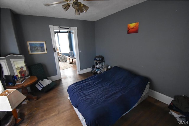 bedroom featuring a ceiling fan, a textured ceiling, baseboards, and wood finished floors