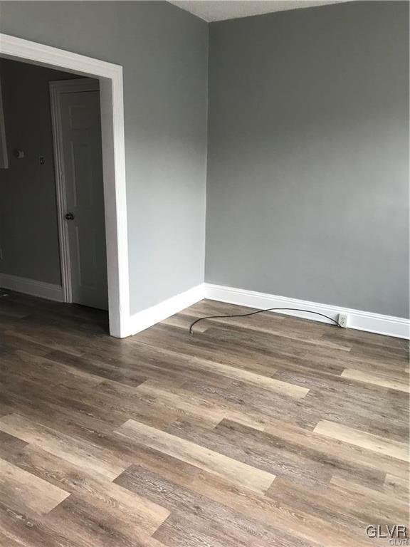 unfurnished room with baseboards and dark wood-style flooring