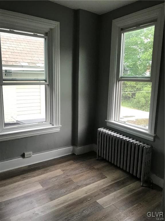 unfurnished room with baseboards, wood finished floors, and radiator