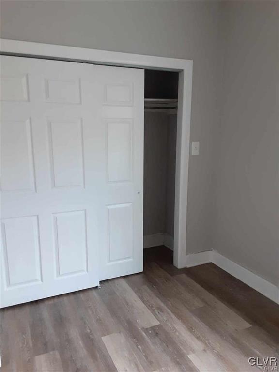 unfurnished bedroom featuring a closet, baseboards, and wood finished floors