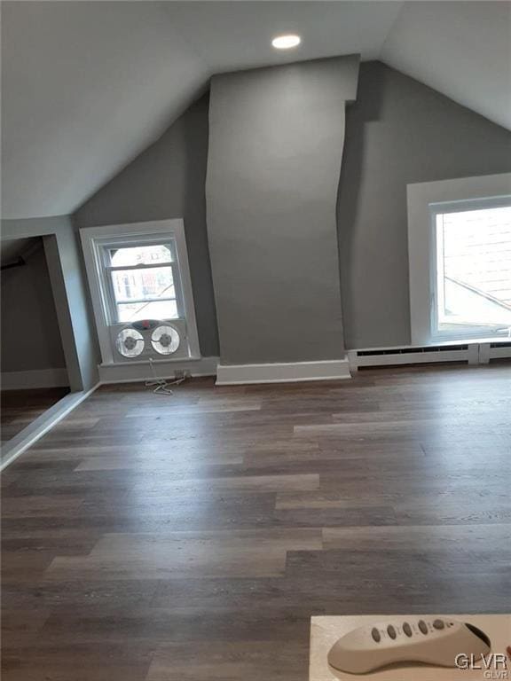 additional living space featuring baseboards, a baseboard heating unit, vaulted ceiling, and wood finished floors