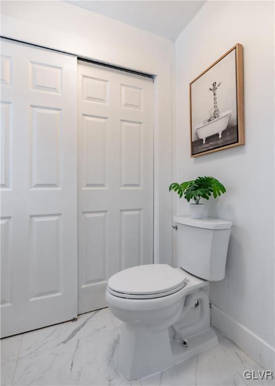 bathroom featuring toilet, marble finish floor, and baseboards