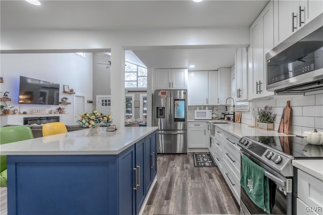 352 Scotch Pine Dr, Coolbaugh Twp, PA 18346 - kitchen featuring stainless steel appliances, blue cabinets, light countertops, open floor plan, and white cabinets