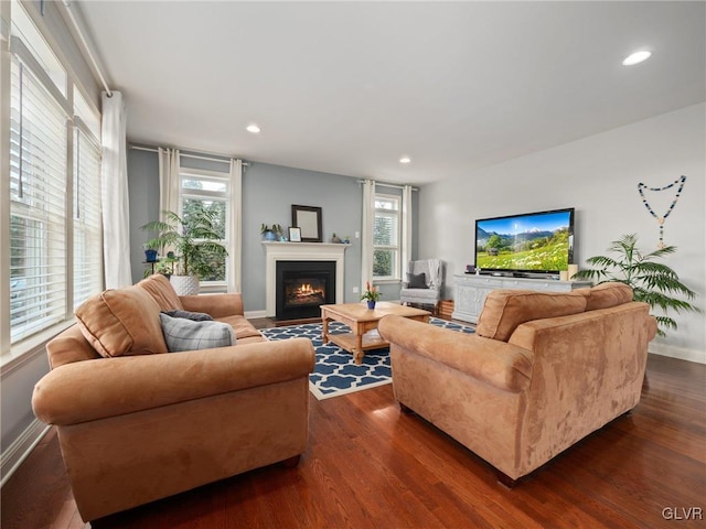 living area with a fireplace with flush hearth, recessed lighting, dark wood-style flooring, and plenty of natural light