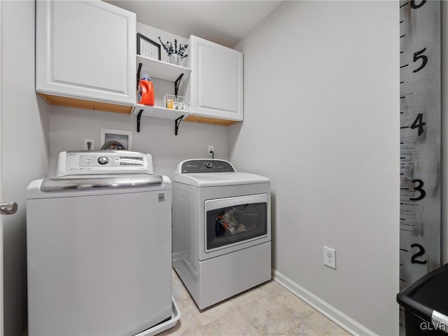 clothes washing area featuring washer and clothes dryer, cabinet space, and baseboards