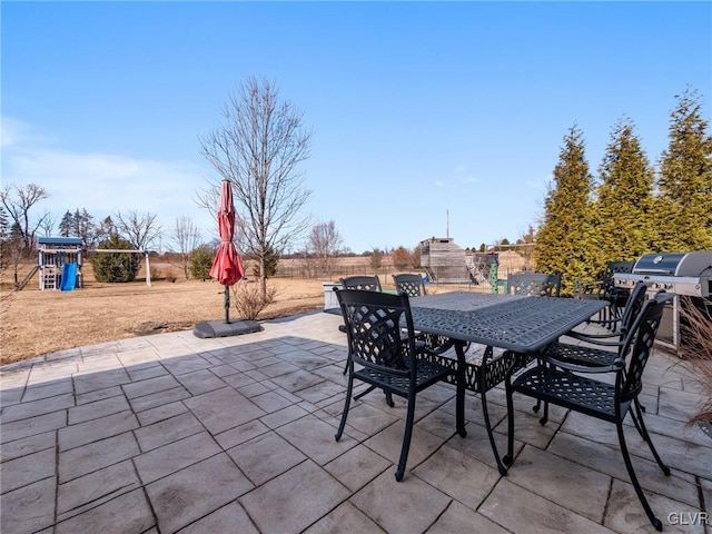 view of patio featuring outdoor dining space, a playground, and a grill