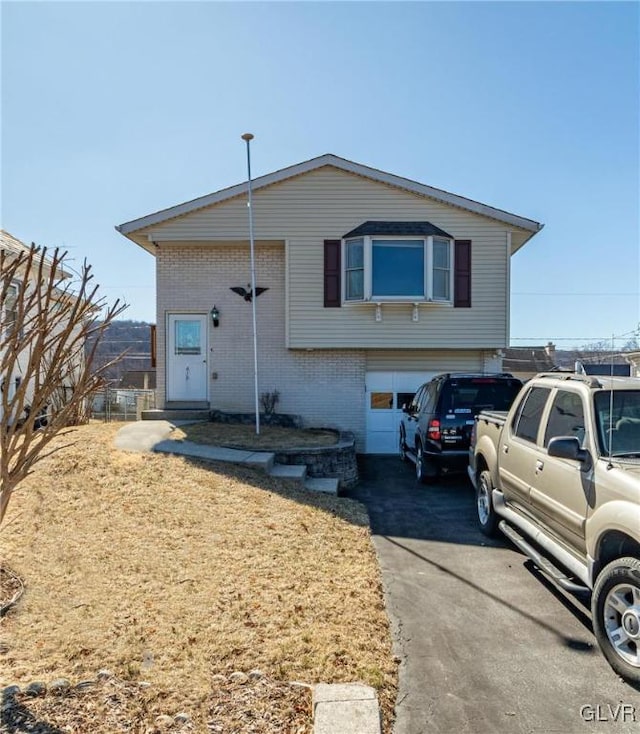 view of front of property with aphalt driveway, an attached garage, and brick siding