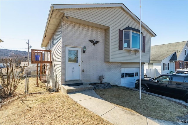 view of front of home with brick siding, fence, and an attached garage