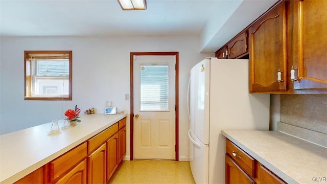 kitchen featuring brown cabinetry, freestanding refrigerator, and light countertops