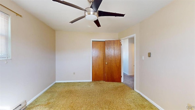 unfurnished bedroom with a baseboard radiator, a closet, light colored carpet, a ceiling fan, and baseboards