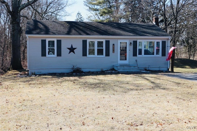 single story home with entry steps, driveway, a chimney, and a front lawn