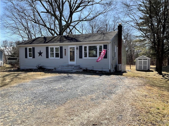 view of front of home featuring an outbuilding, a storage unit, driveway, and a chimney