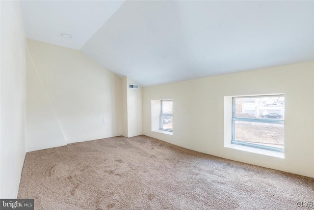 carpeted spare room with lofted ceiling and visible vents