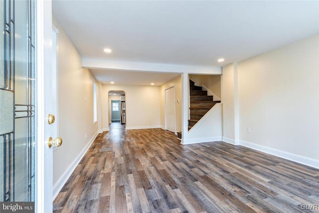 interior space featuring arched walkways, recessed lighting, wood finished floors, baseboards, and stairs