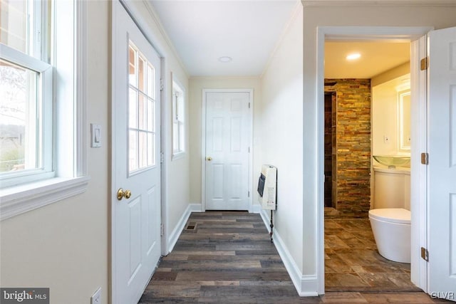 doorway with ornamental molding, dark wood-style flooring, baseboards, and heating unit