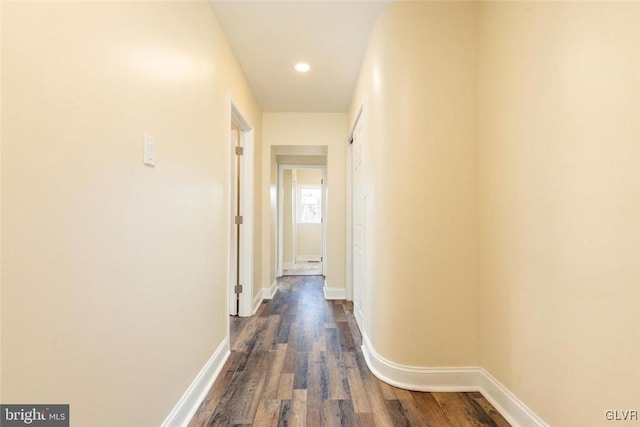 corridor featuring dark wood-type flooring and baseboards