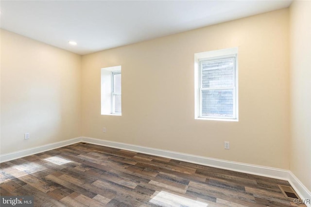 spare room with visible vents, baseboards, and dark wood-style flooring