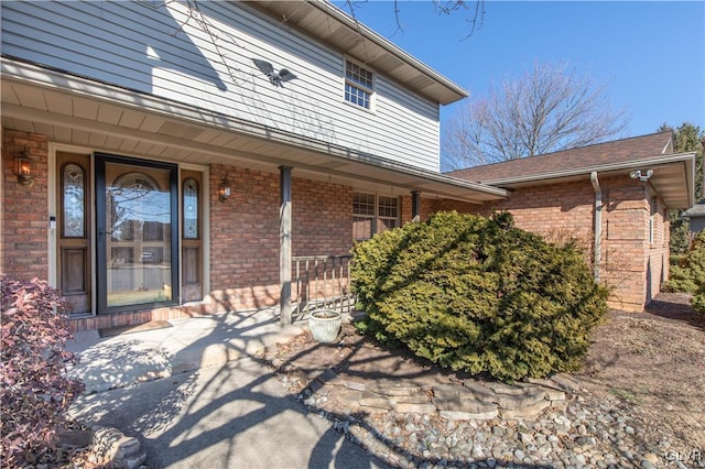 doorway to property with covered porch and brick siding