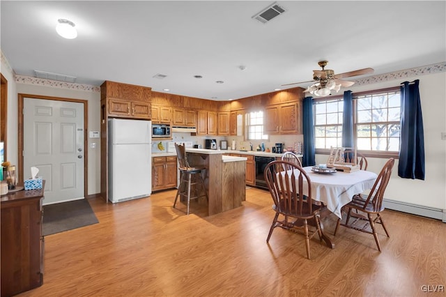 dining area featuring a baseboard heating unit, visible vents, light wood-style flooring, and a ceiling fan