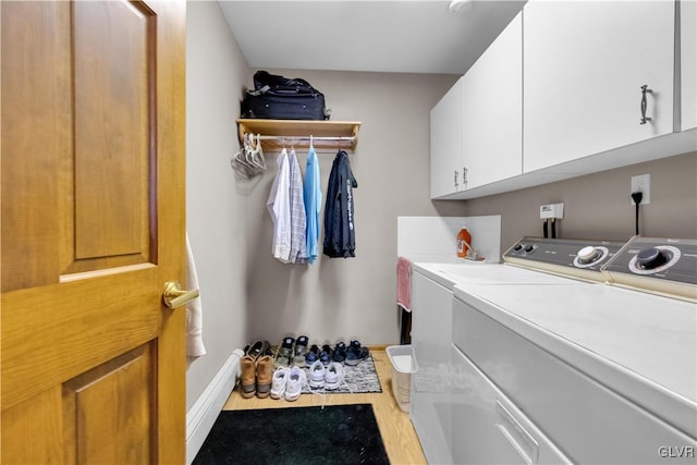 clothes washing area with washer and dryer, cabinet space, baseboards, and wood finished floors