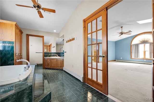 full bath with a baseboard radiator, a tub with jets, tile patterned flooring, and vanity