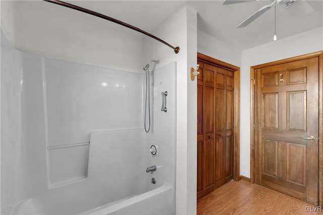 bathroom with washtub / shower combination, a ceiling fan, and wood finished floors