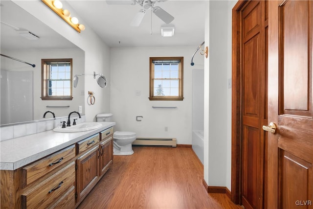 full bath with toilet, shower / tub combination, a baseboard heating unit, and wood finished floors