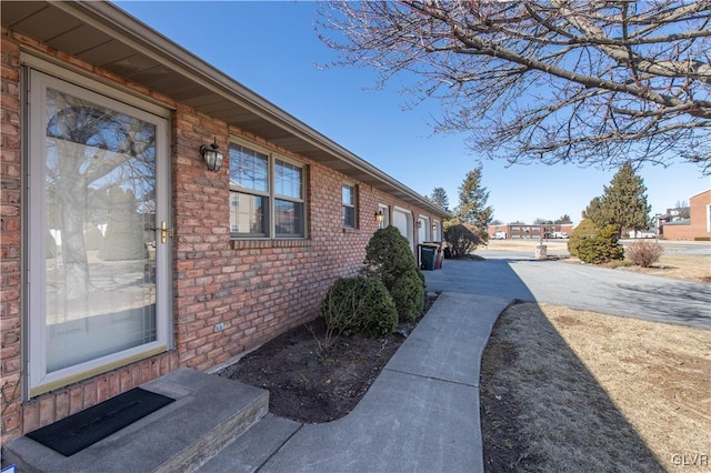 view of side of home featuring concrete driveway, brick siding, and an attached garage