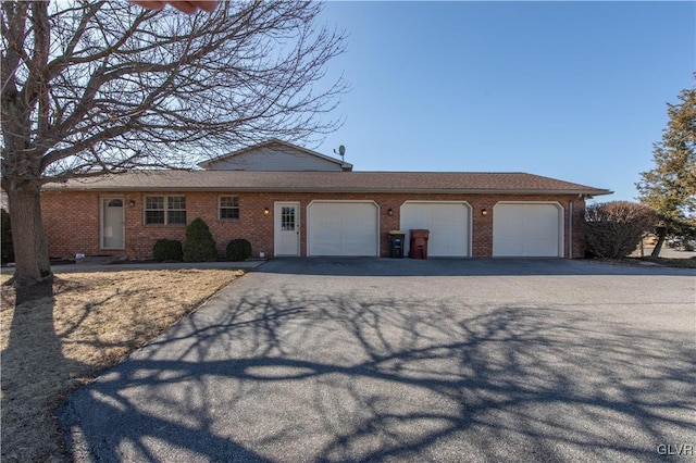 single story home featuring a garage, driveway, and brick siding