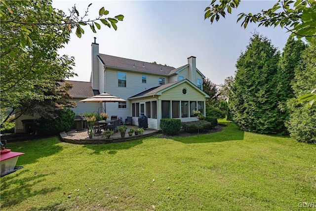 rear view of property with a sunroom, a patio, a chimney, and a lawn