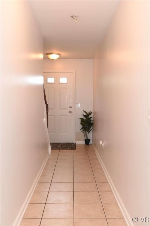 doorway featuring light tile patterned flooring and baseboards