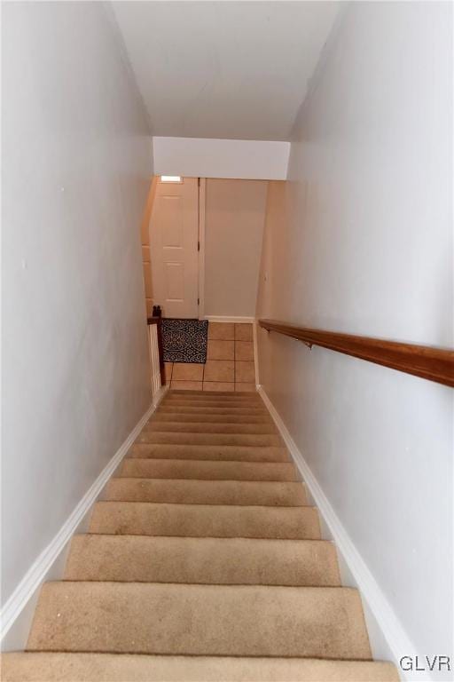 staircase featuring baseboards and tile patterned floors