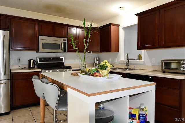 kitchen featuring a toaster, a kitchen island, stainless steel appliances, light countertops, and a sink