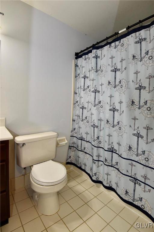 full bathroom with a shower with shower curtain, vanity, toilet, and tile patterned floors